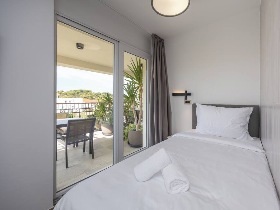 Una habitación de hotel con una cama, vistas al balcón y un comedor con mesa y sillas.