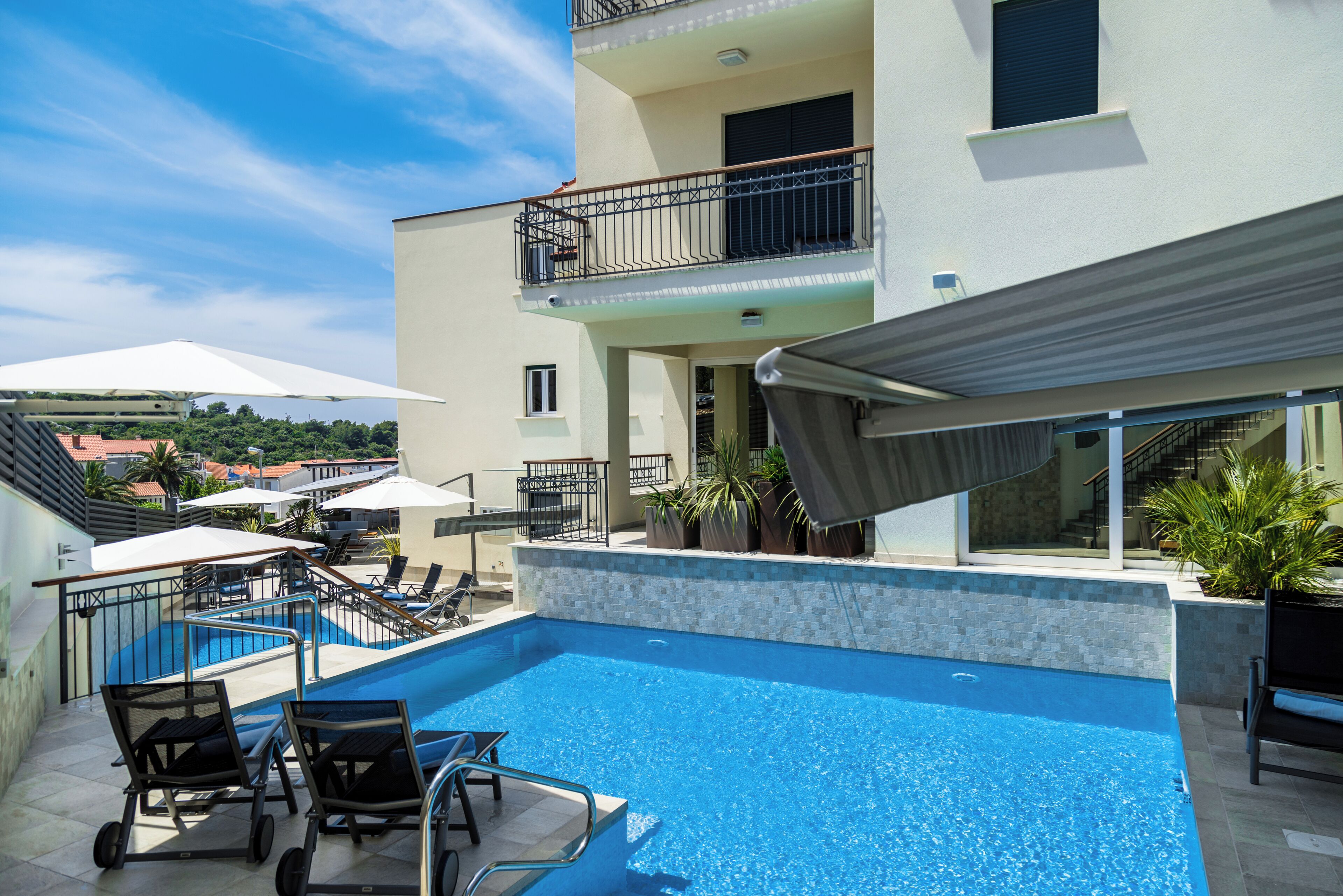 Una piscina sul tetto con lettini, una zona relax coperta e vista sugli edifici circostanti.
