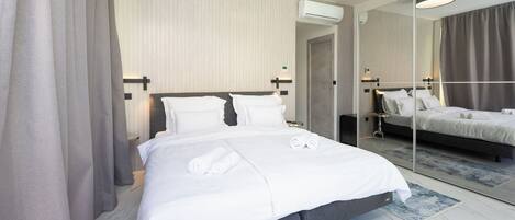 A modern hotel room with a large bed, a mirror, and a ceiling light.