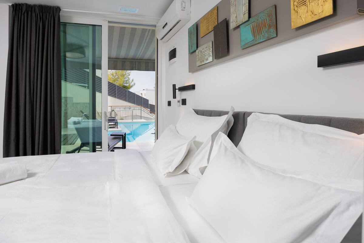 Habitación de hotel con una cama grande, vista a una piscina y un balcón.