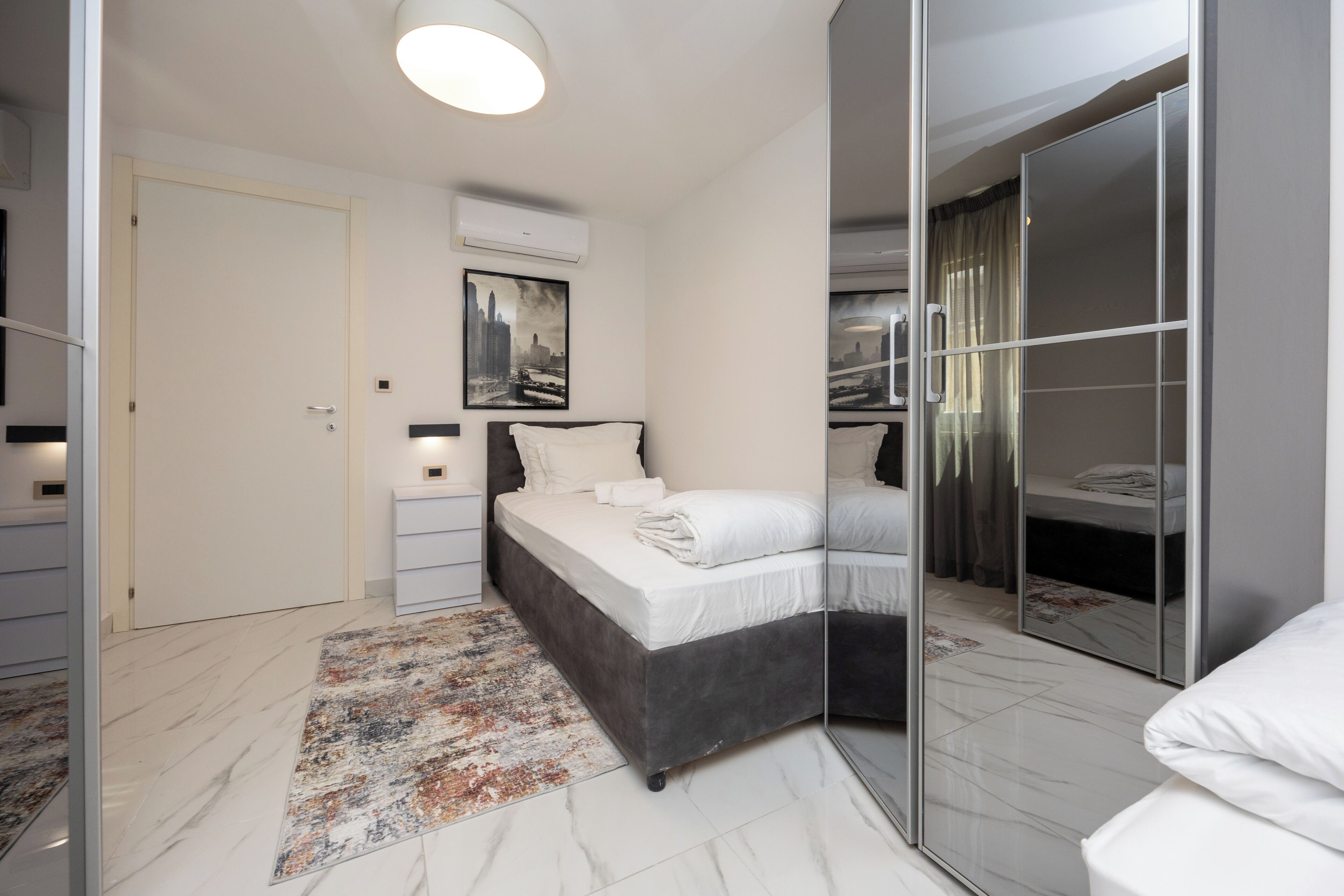 Un dormitorio moderno con cama, mesitas de noche, un espejo y un armario.