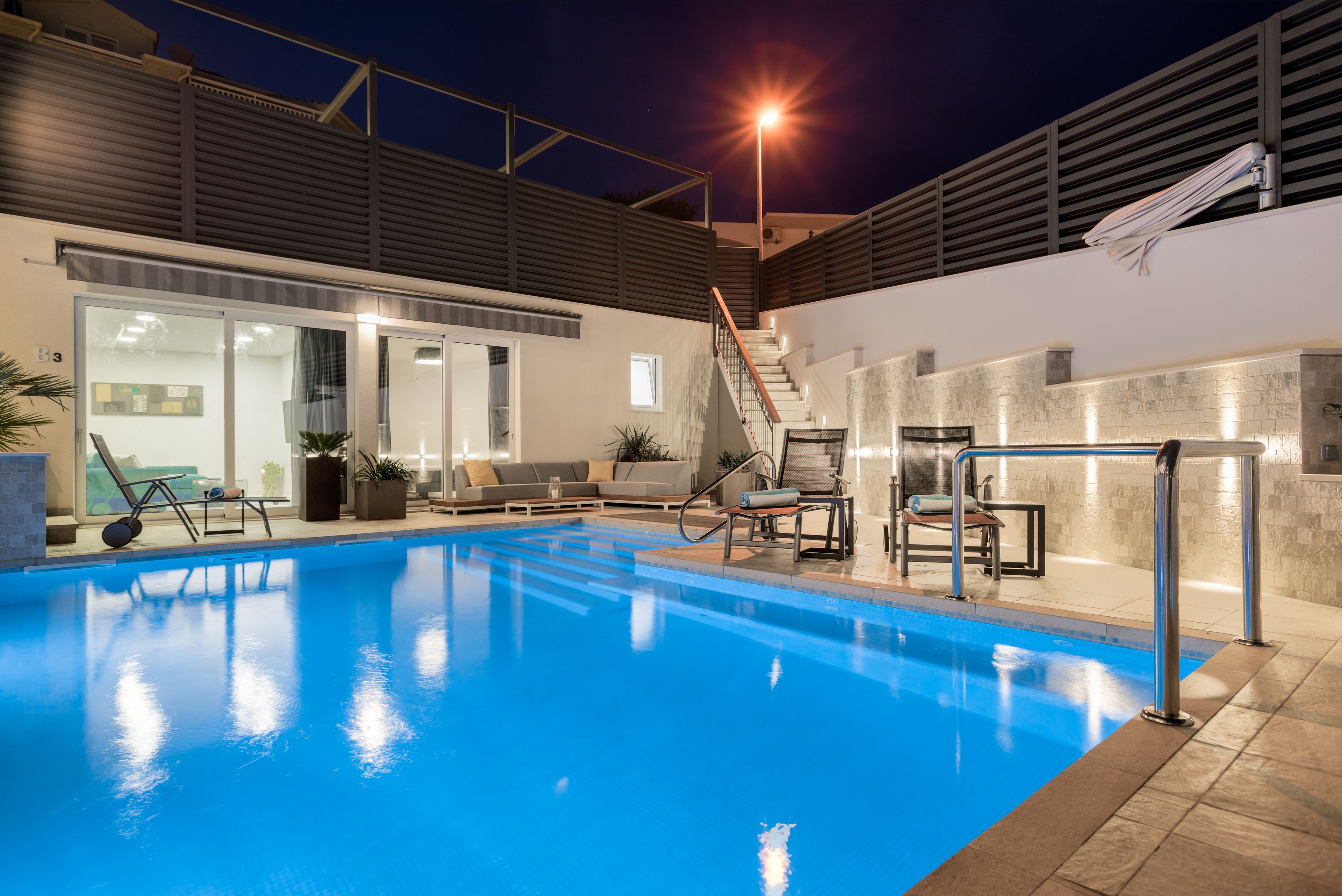 Una piscina interior amb una vista clara de l'edifici proper, una escala i una zona d'estar amb seients.