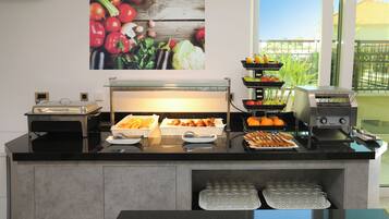 A buffet setup with various food items and a coffee machine.