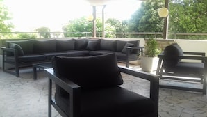 An outdoor seating area with a sectional sofa, a single chair, and a small table. - Park Hotel (Camaiore)