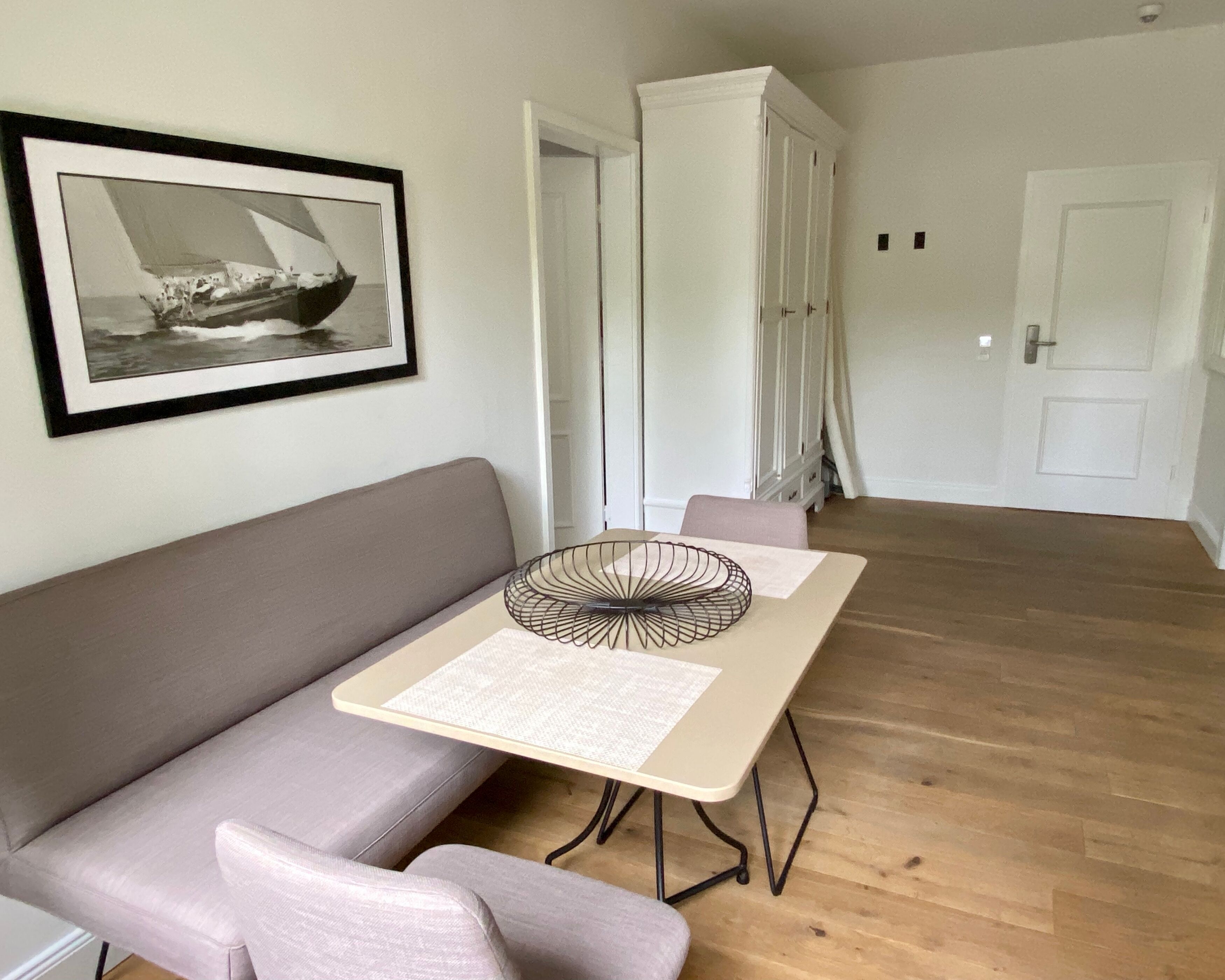 A modern living room with a grey sofa, a small table with a decorative item, and a framed picture on the wall.