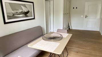 A modern living room with a grey sofa, a small table with a decorative item, and a framed picture on the wall.
