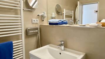 A bathroom with a white sink, towel racks, a mirror, and a towel dispenser.