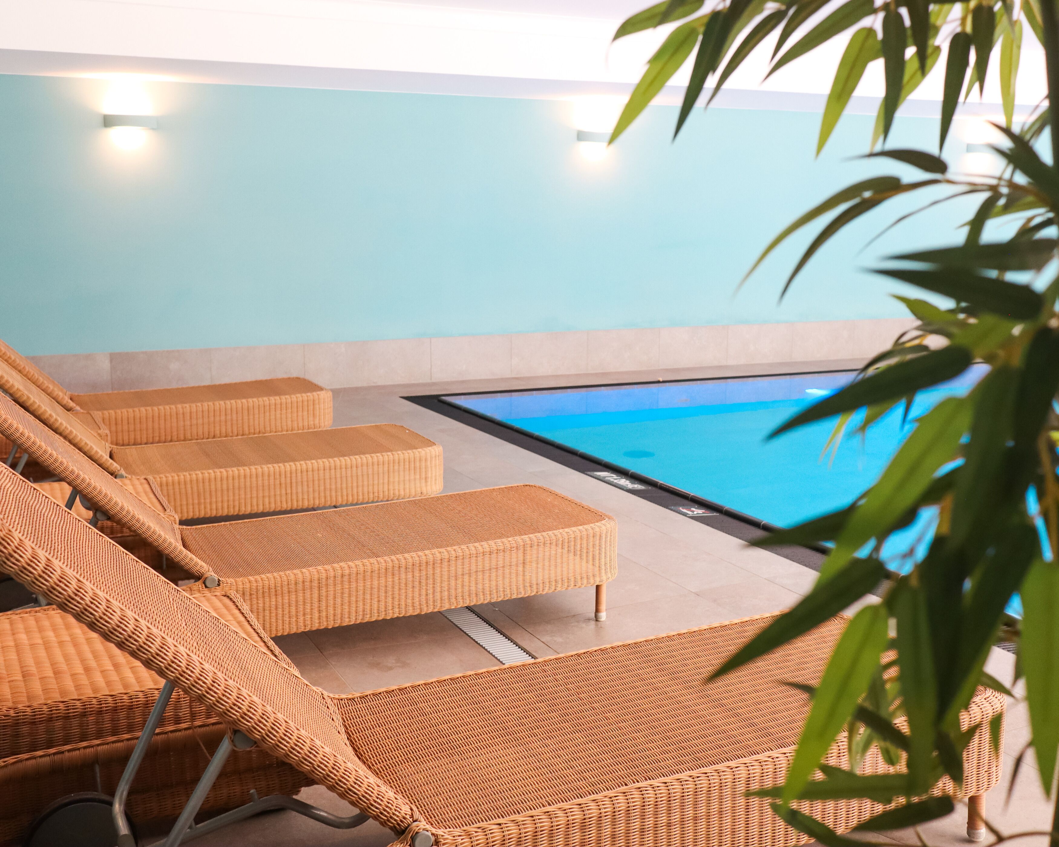 Un área junto a la piscina con sillones de mimbre y una vista despejada del agua.
