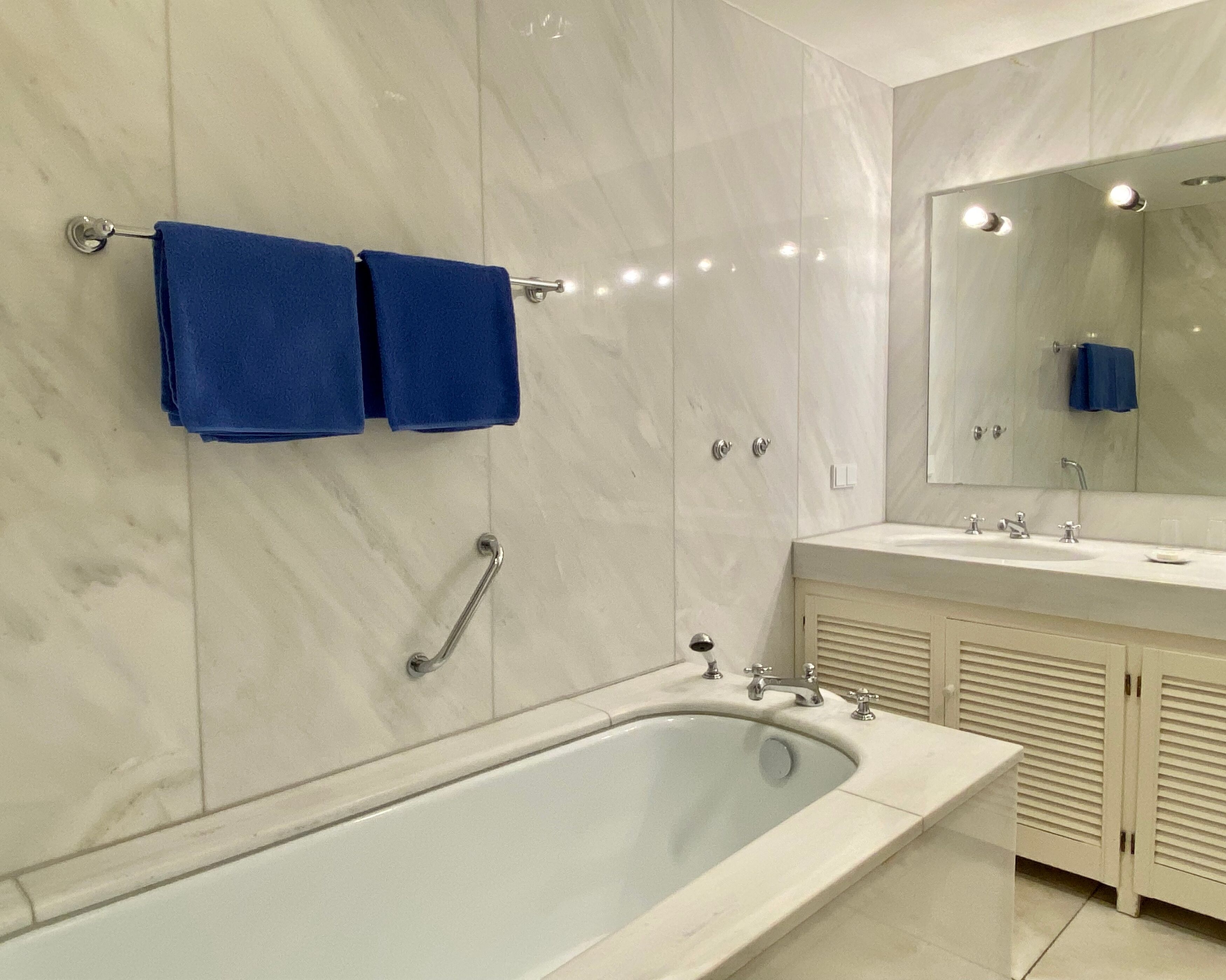 A modern bathroom with a large bathtub, a vanity with a mirror, and two towels hanging on a towel rack.