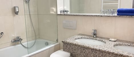 A modern bathroom with a glass-enclosed shower, a white toilet, and a granite countertop sink.