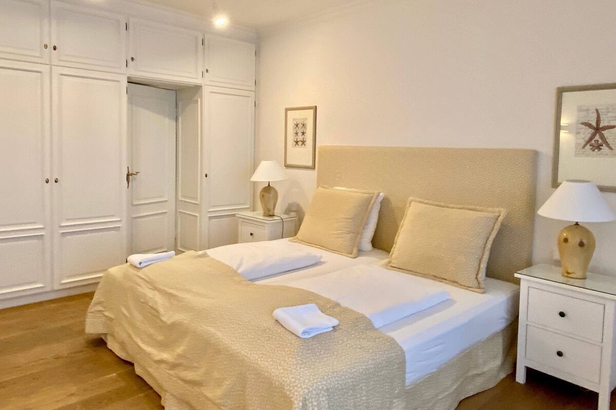 A bedroom with a large bed, two bedside tables, a wardrobe, and a framed picture on the wall.