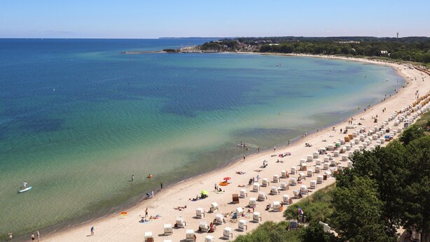A beach with numerous white tents and a sandy shoreline.