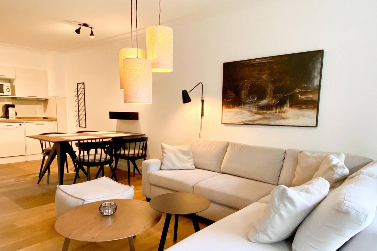 A modern living room with a sofa, coffee table, and dining area.