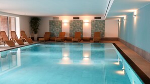 A swimming pool with lounge chairs and wall art.