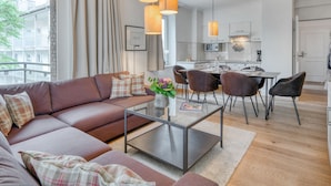 A modern living room with a sofa, a glass coffee table, and a dining area with chairs and a table.