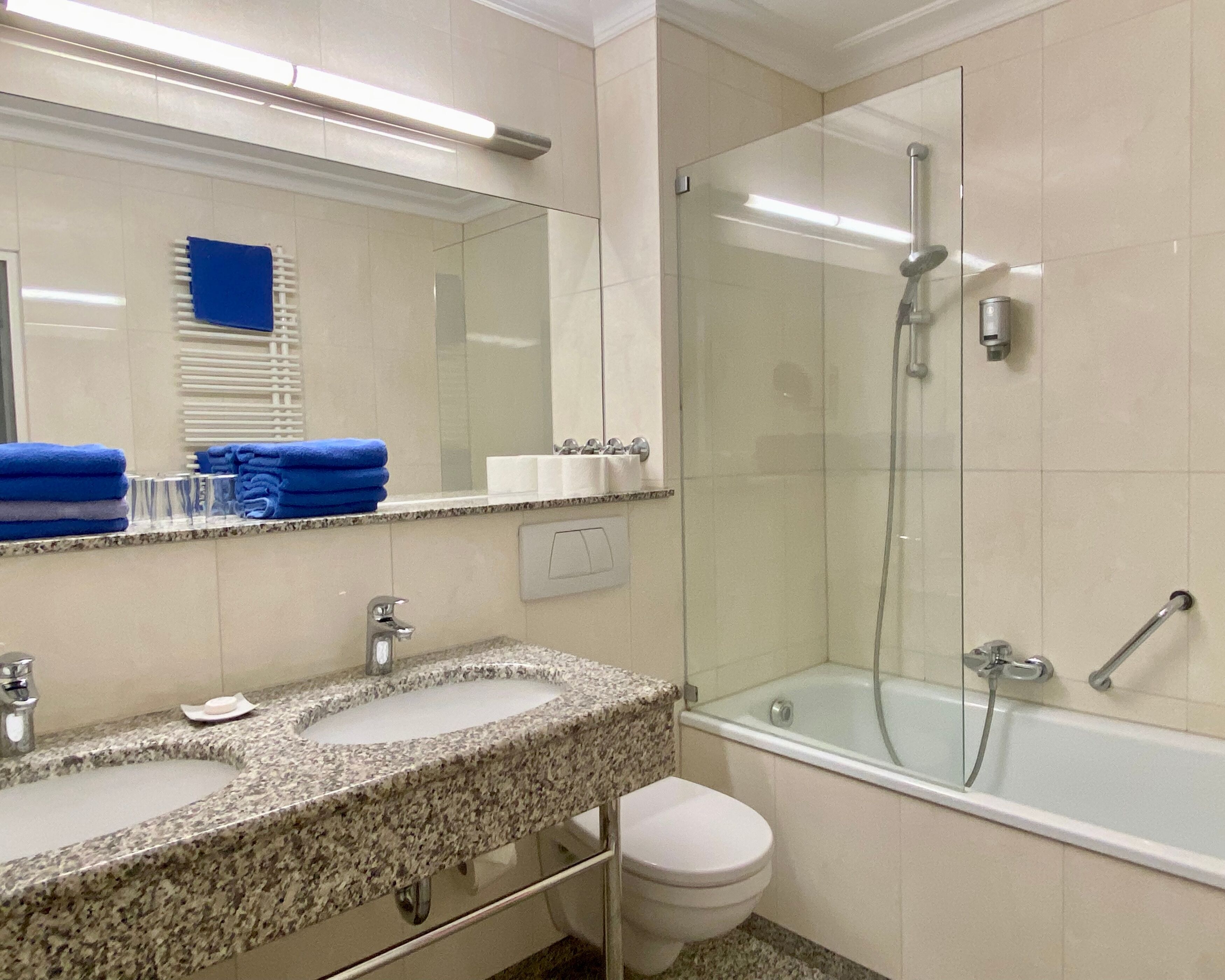 Un bagno con lavabo su piano in granito, uno specchio, cabina doccia in vetro e un water.