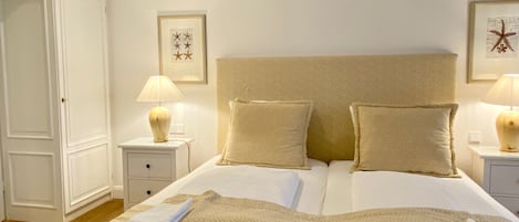 Una cama bien hecha con dos almohadas, una mesita de noche con lámpara y un armario.