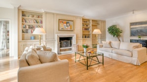 A spacious living room with a fireplace, bookshelves, a coffee table, and a sofa.