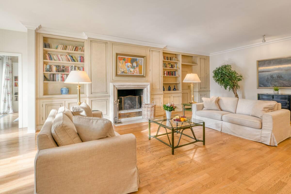 A spacious living room with a fireplace, bookshelves, a coffee table, and a sofa.