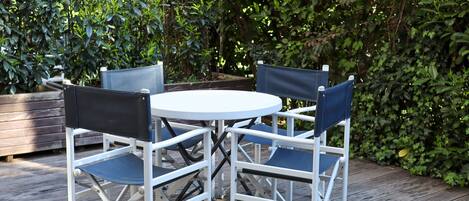 Een ronde tafel met vier stoelen, geplaatst op een houten terras.