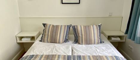 A hotel room with a large bed, striped bedding, two bedside tables with lamps, and a framed picture on the wall.