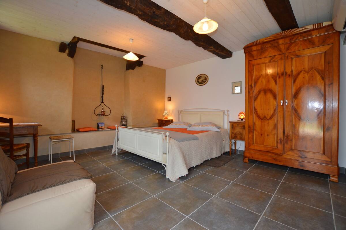 Une chambre à coucher avec un lit, une armoire en bois, un bureau et une chaise.