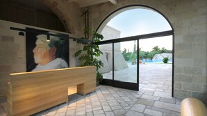 Un espace d’accueil avec un banc en bois, un grand tableau et une porte vitrée donnant sur l’extérieur.
