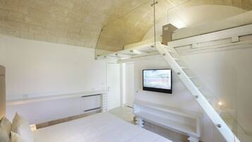 Quarto com cama, televisão fixada na parede e escada.