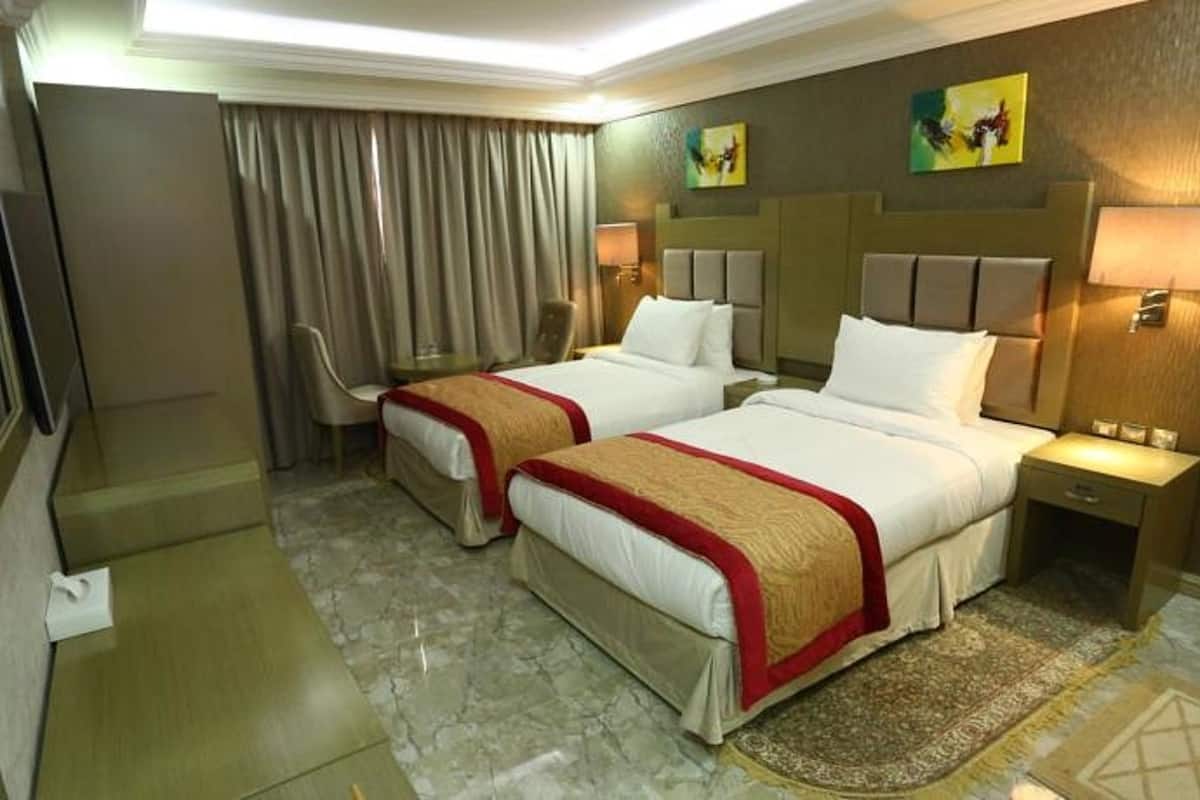 Une chambre d’hôtel avec deux lits, une télévision, un bureau et une chaise.