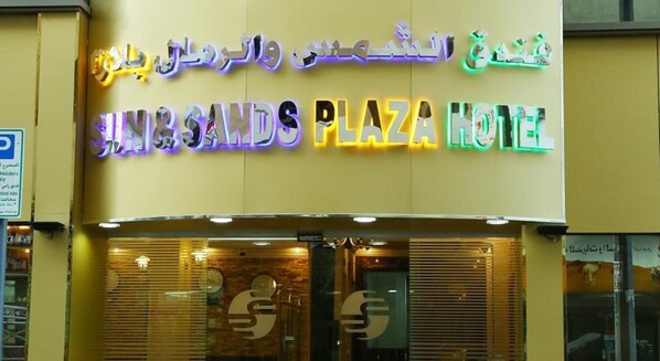 The exterior of the Sun & Sands Plaza Hotel with illuminated signage in multiple languages.