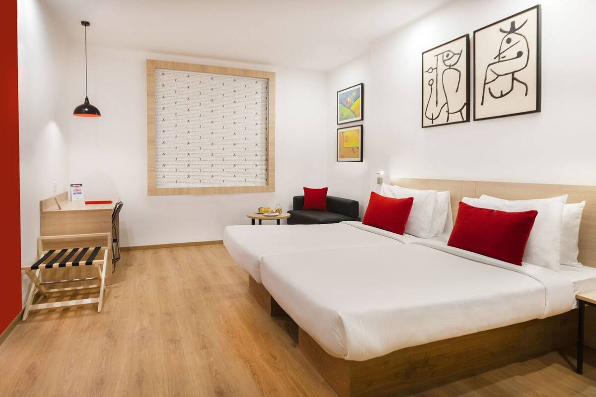Een hotelkamer met een bed, een bureau, een stoel, een tafeltje en kunst aan de muren.