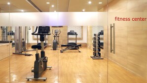 Un centre de remise en forme équipé de matériel d’exercice, doté de planchers en bois et d’un mur recouvert de miroirs.
