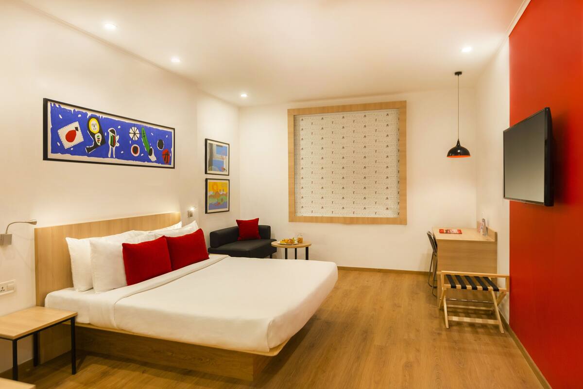 Een moderne hotelkamer met een groot bed, een bureau, een stoel, een tafeltje en een televisie.