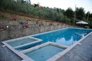 Piscina retangular com parede de pedra e caixas de flores.