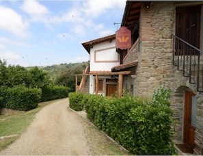 A stone building with a wooden balcony and a sign. - Agriturismo La Casella (Castelfranco Piandisco)