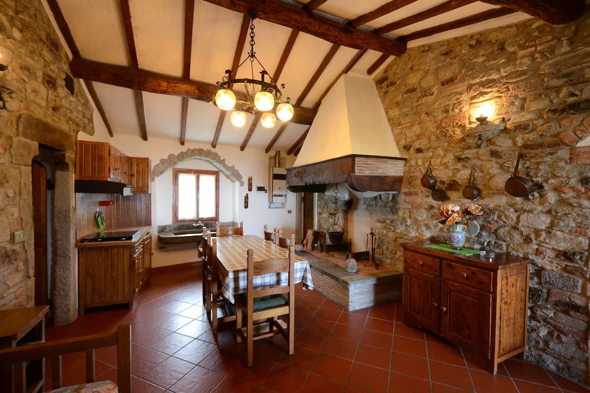 Eine rustikale Küche mit Holztisch, Stühlen und einer Steinwand.