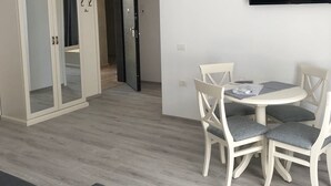 Ett modernt vardagsrum med en matplats, en tv som är monterad på väggen och en garderob med en spegel.