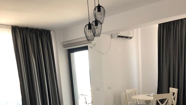 Ett rymligt vardagsrum med ett matbord och stolar, en svart soffa och en taklampa.