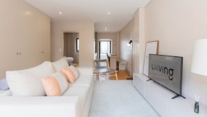 Uma sala de estar moderna com sofá, TV e área de jantar.