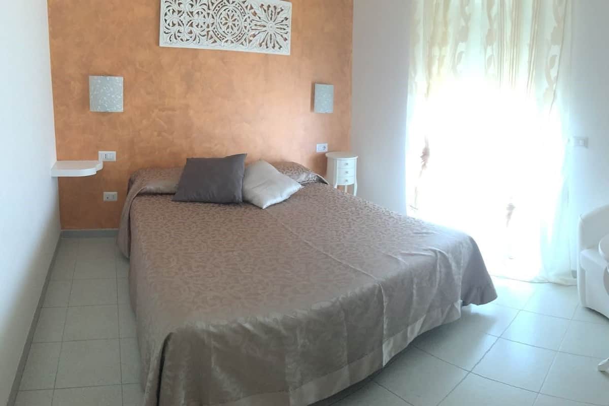 Ein Schlafzimmer mit einem Bett, einem Nachttisch, einem Sessel und einer Wanddekoration.