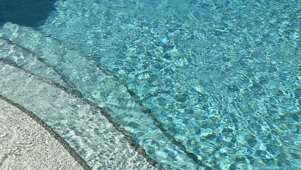 Una piscina nítida amb un vorejador i una passera enrajolada que hi convergeix.