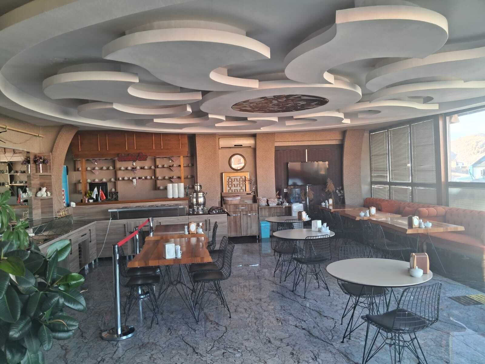 Un interior moderno con zona de cocina, mesas de comedor y asientos.