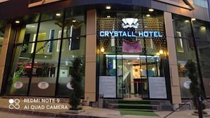The exterior of the Crystal Hotel with a modern design, featuring a glass facade and a prominent neon sign. - Crystall Hotel (Van)