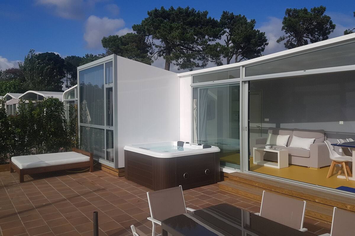 Eine moderne Außenpatio mit Whirlpool, Sitzgelegenheit und einem gläsernen Wohnbereich.