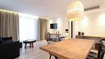 Un salón moderno con un gran comedor de madera, un sofá y un televisor montado en la pared.