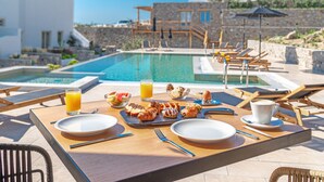 Desayuno con vista a la piscina, que incluye una mesa con platos, cubiertos y un vaso de jugo de naranja.