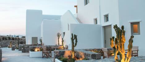 A modern white building with a stone courtyard, outdoor seating, and cacti.