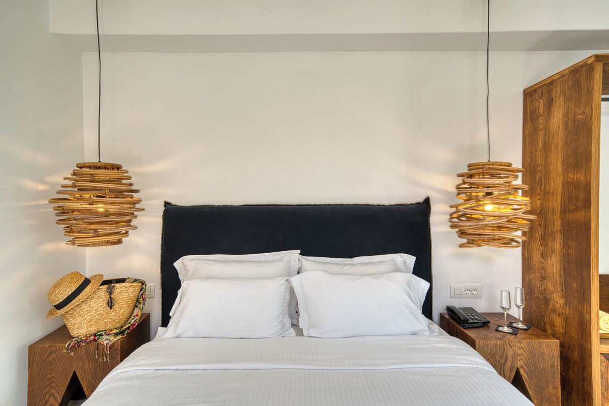 A bed with white linens, a dark headboard, and two bedside tables with wicker lamps.