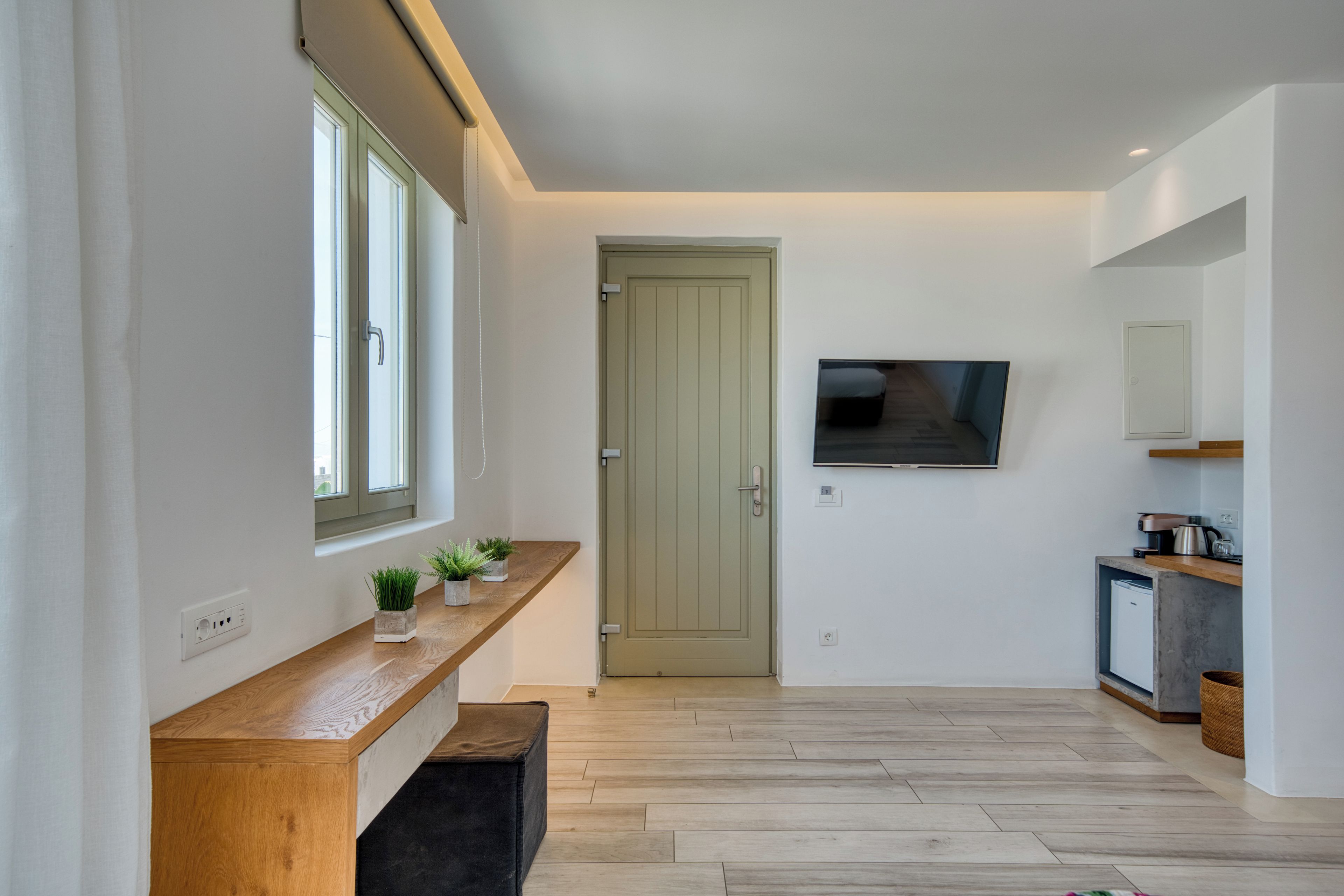 A modern kitchen with a wooden countertop, a built-in oven, and a television mounted on the wall.