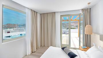 A hotel room with a large bed, a view of the city, and a balcony with a hot tub.